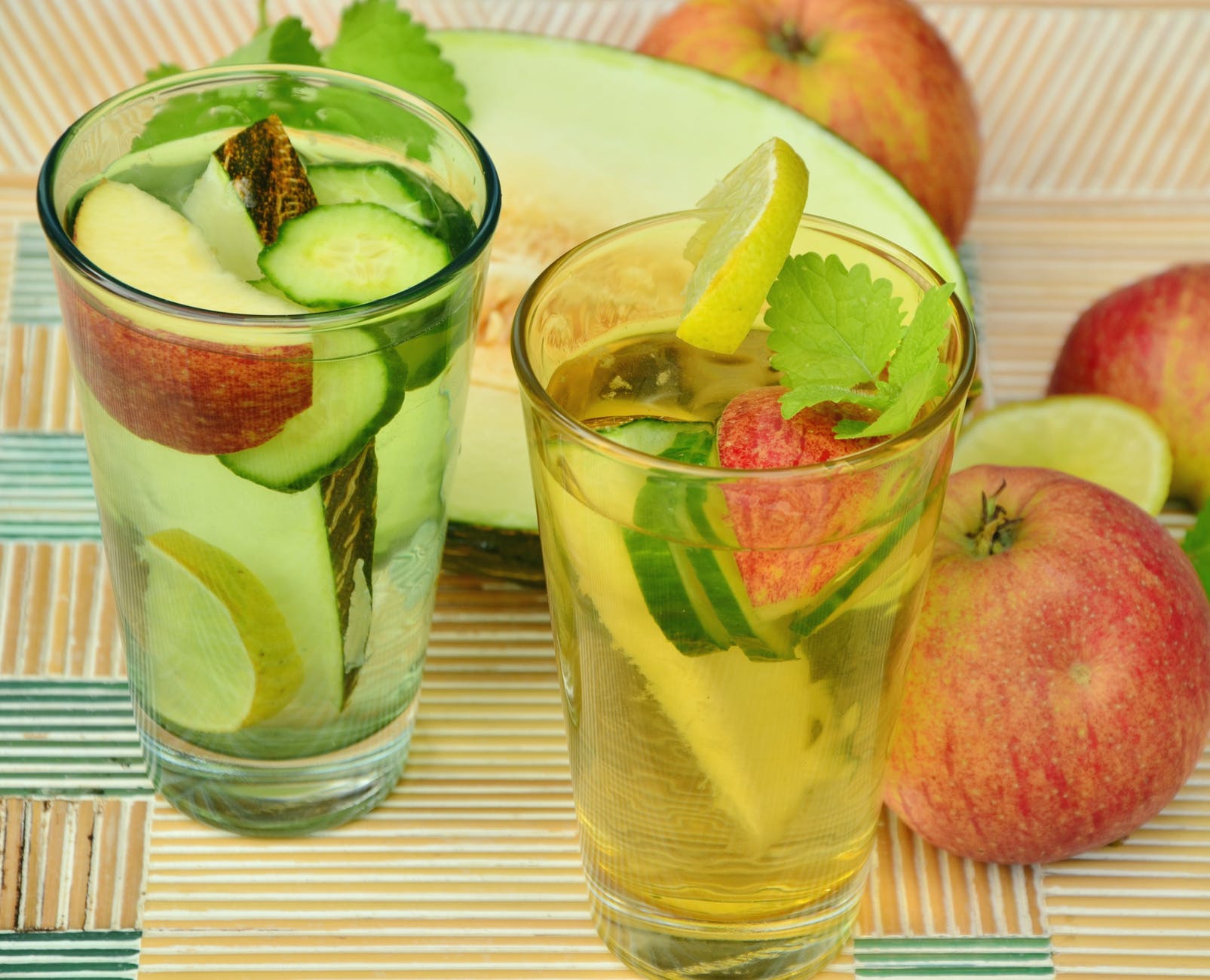 clear glass cup with fruits and water inside beside slice fruitas