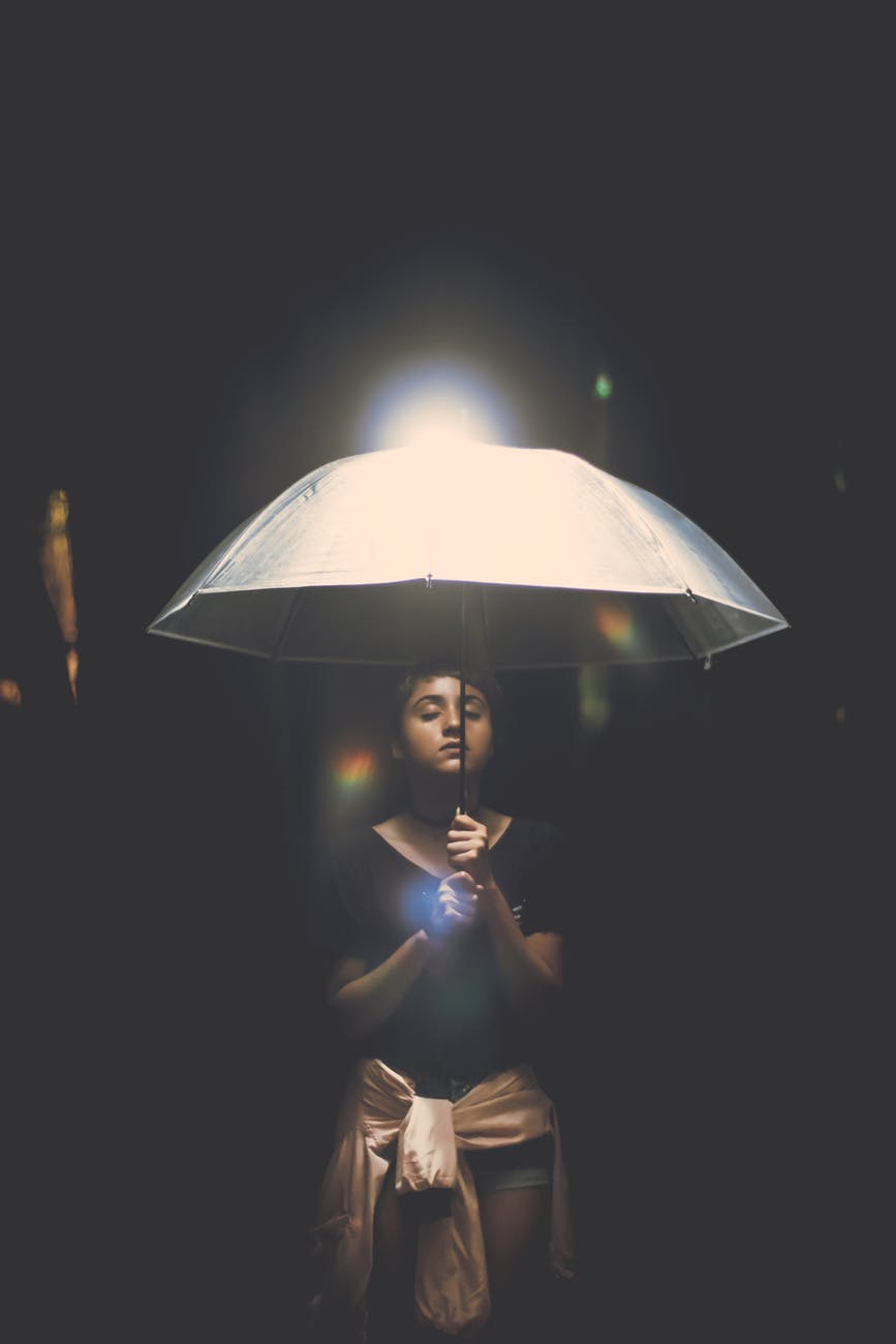 woman holding illuminated lamp at night