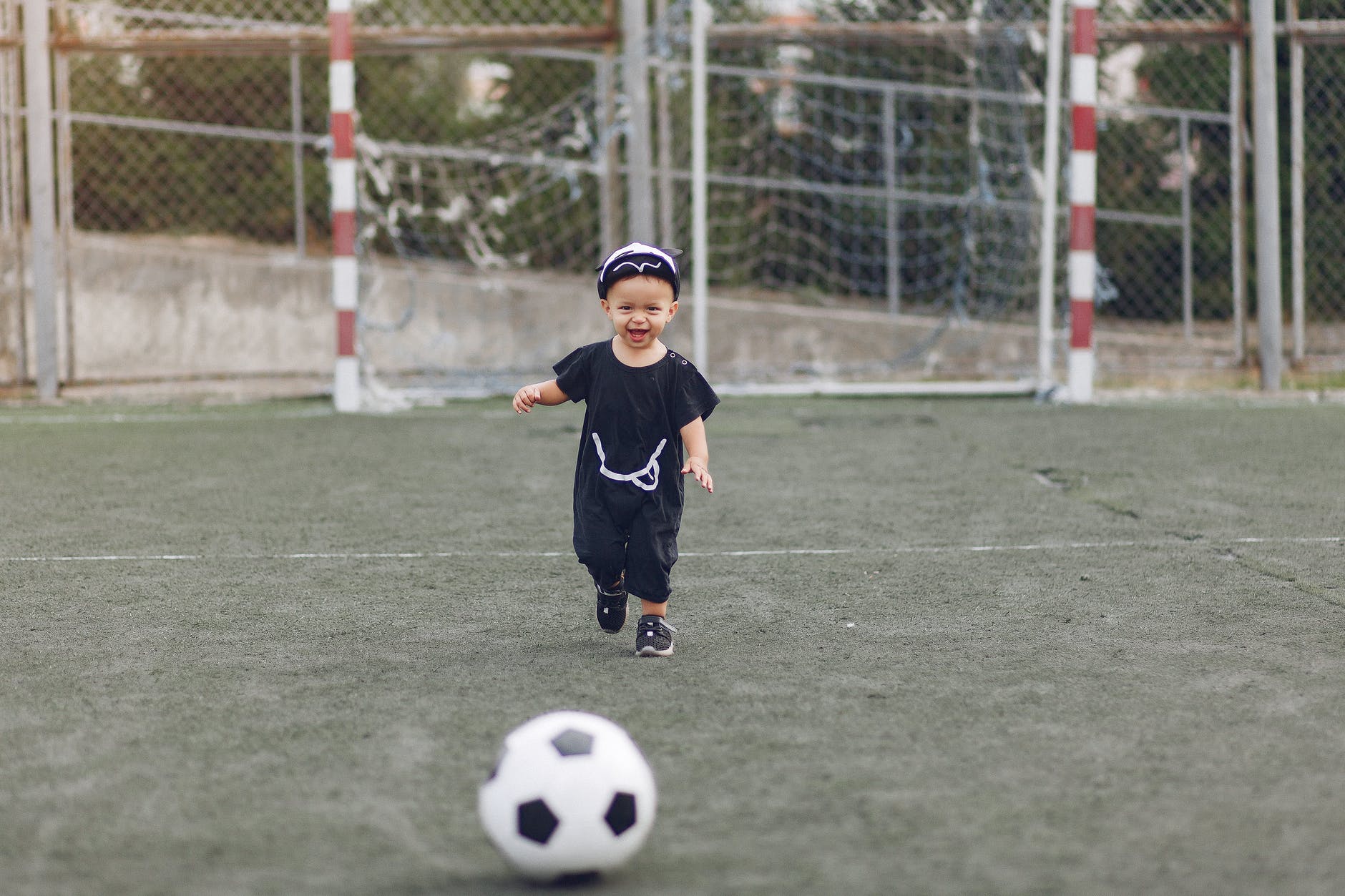 cute little boy with football ball on sports ground