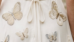 Bride seen from behind wearing a butterfly-embroidered wedding dress in a garden
